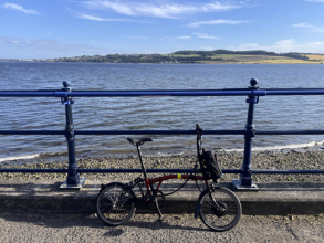 A photograph of the sea and beach, with a bicycle parked against a railing