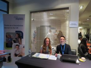 Two foundation school managers sat at a welcome desk, smiling