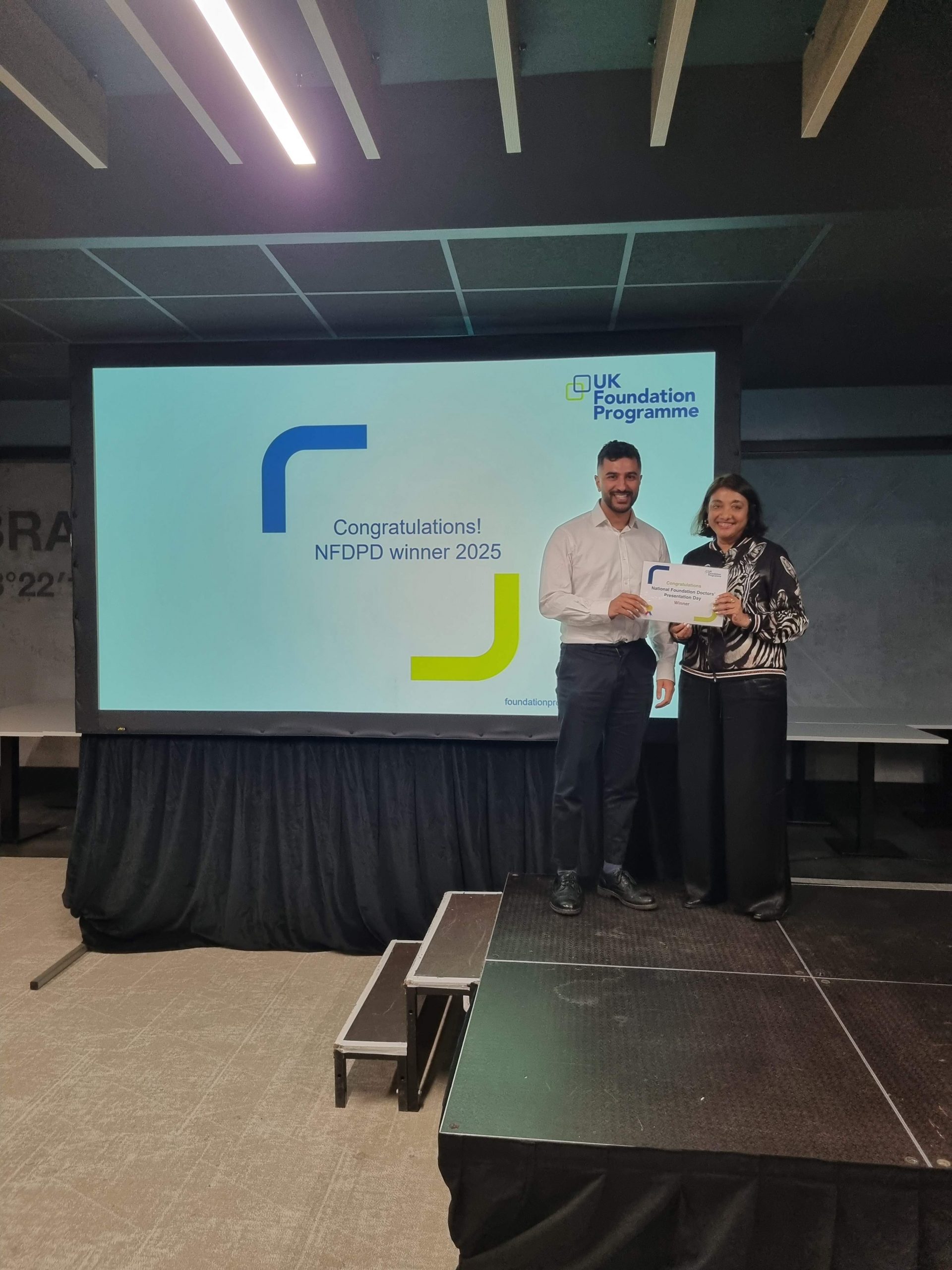 Image of Dr Kishan Lakhani winner of their presentation group receiving their certificate presented by Dr Navina Evans
