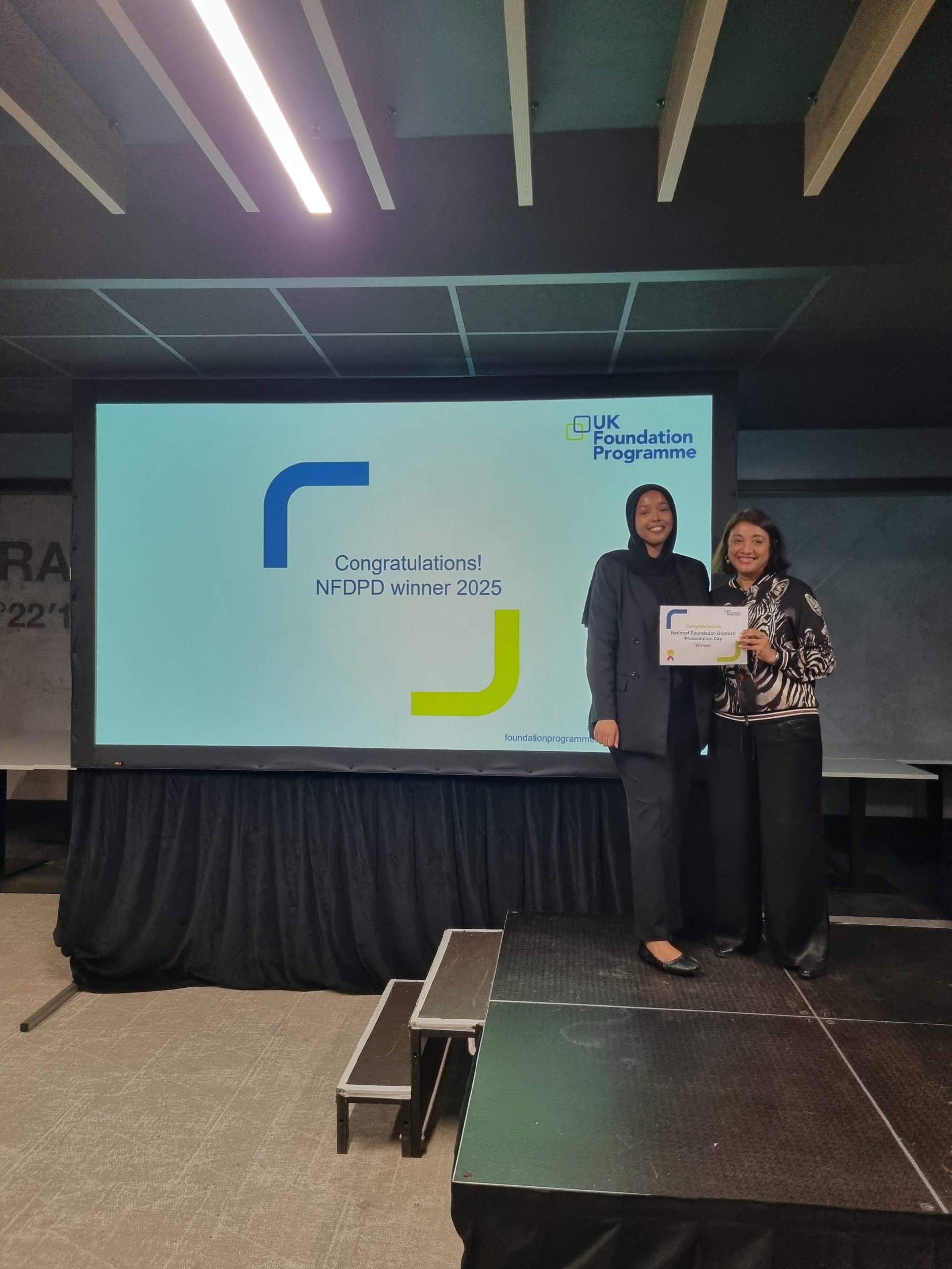 Image of Dr Sumeya Faysal winner of their presentation group receiving their certificate presented by Dr Navina Evans