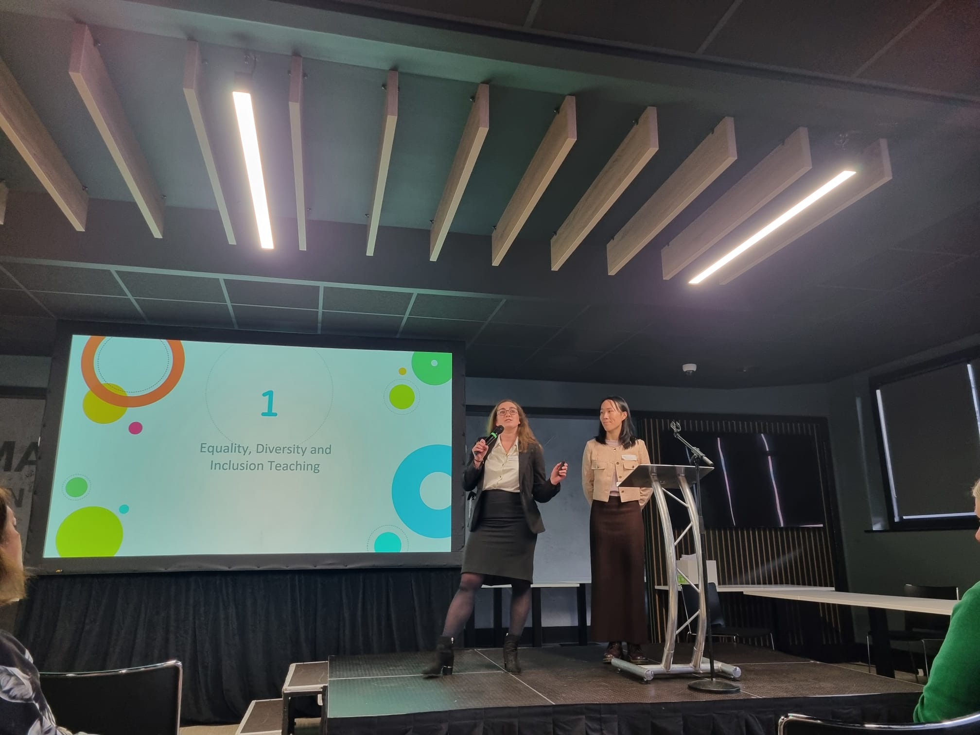 Dr Dasha Ibrahim at the podium in the main hall presenting her UKFPO Fellow project