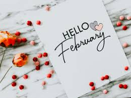 Phrase 'Hello February' on a white piece of paper with red decoration in the background