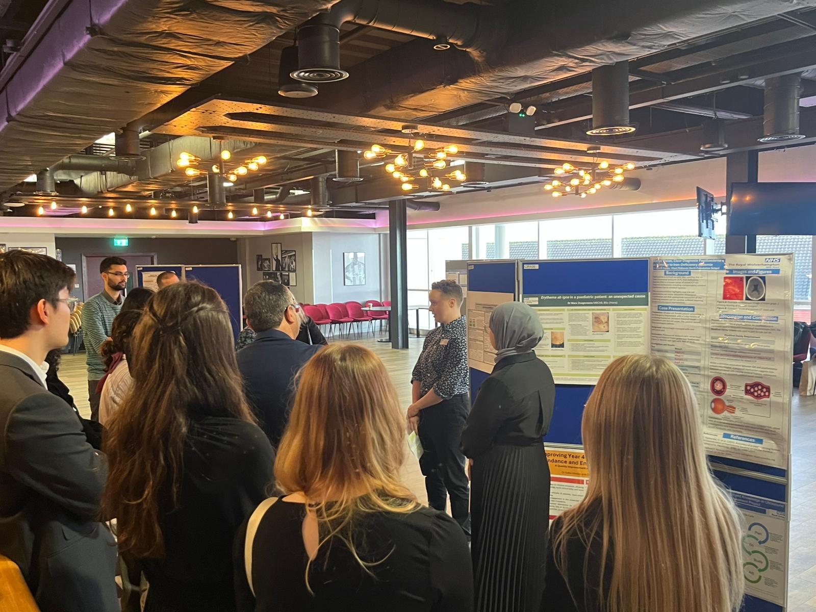 Image of foundation doctors listening to a poster board presentation