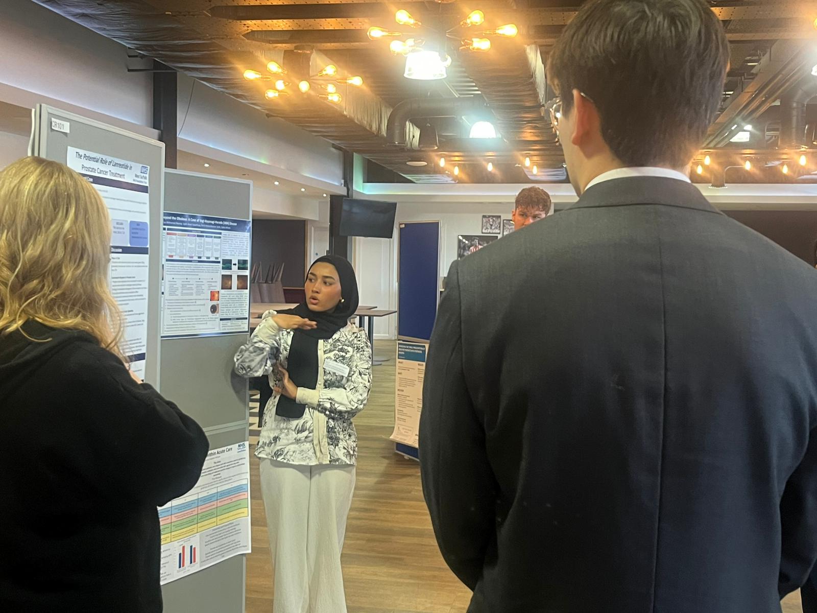 Image of foundation doctors listening to a poster board presentation