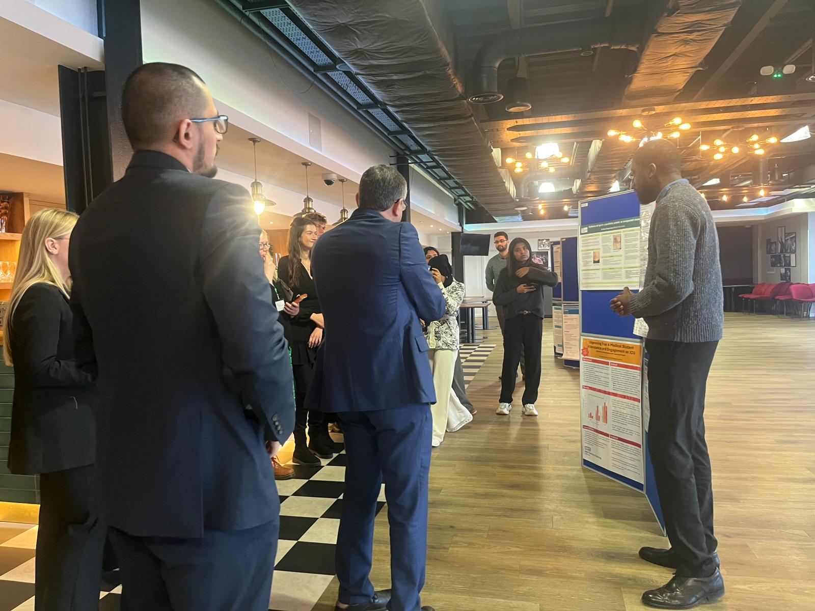 Image of foundation doctors listening to a poster board presentation