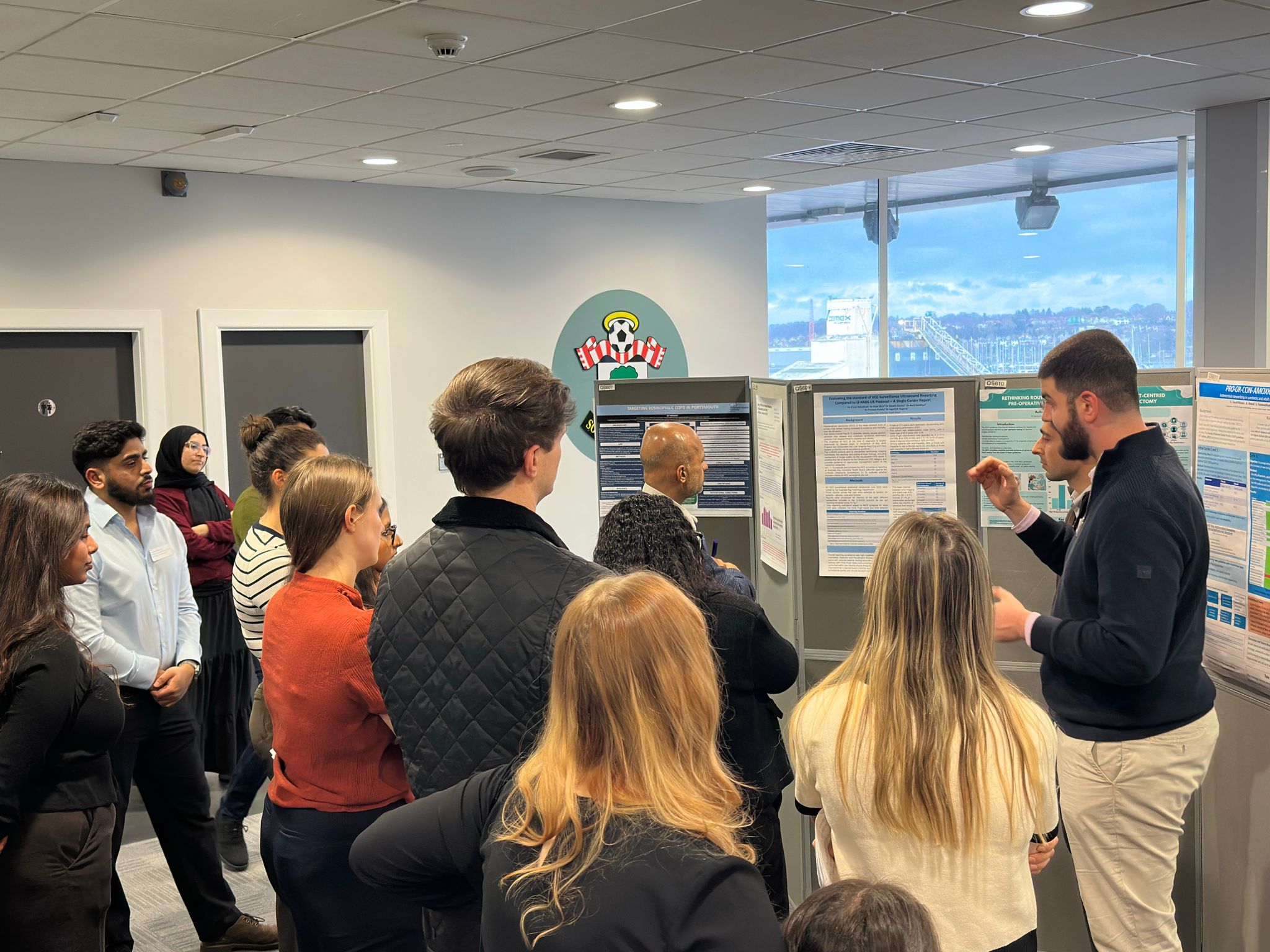 Image of foundation doctors listening to a poster board presentation