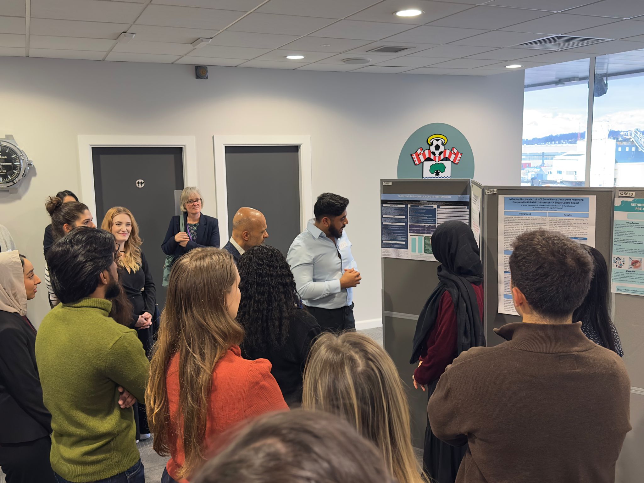 Image of foundation doctors listening to a poster board presentation